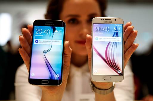 An employee holds up a new Galaxy S6 Edge left and a Galaxy S6 smartphone device following their launch