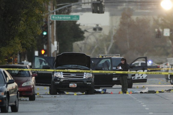 An investigator looks at a black SUV involved in a police shootout with the suspects