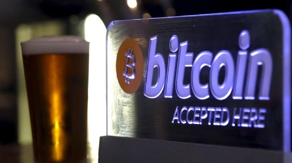 A beer poured for a customer sits on a bar next to a Bitcoin sign in central Sydney Australia