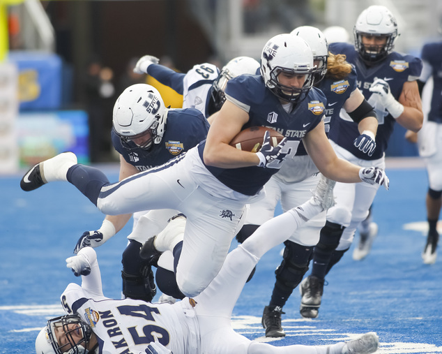 Utah State tight end Wyatt Houston falls over Akron linebacker Dylan Evans during the first half of the Idaho Potato Bowl NCAA college football gam