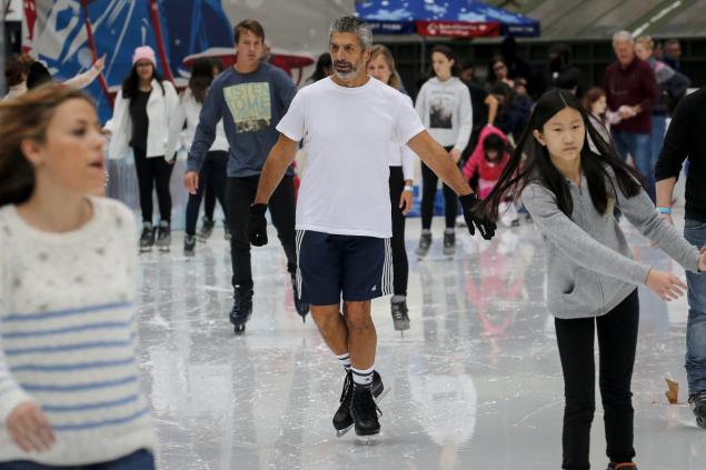 A man skates in shorts and a T-shirt at the skating rink in Bryant Park during unseasonably warm weather on Christmas Eve