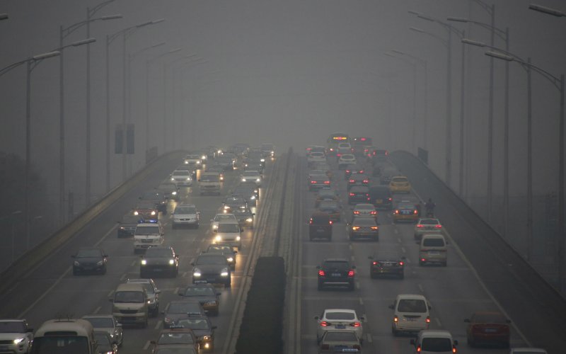 Vehicles using lights travel on a bridge amid heavy smog after the city issued its first ever'red alert for air pollution in Beijing China