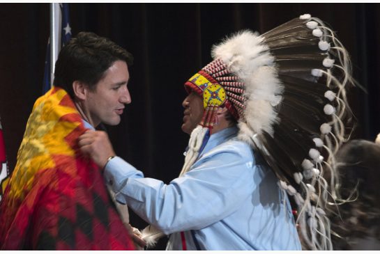 AFN National Chief Perry Bellegarde adjusts a blanket presented to Prime Minister Justin Trudeau following speeches at the Assembly of First Nations Special Chiefs Assembly in Gatineau on Tuesday