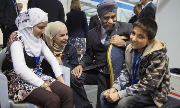 Canadian Minister of National Defence Harjit Sajjan chats with members of a Syrian refugee family at a refugee processing center in Amman Jordan on 29 November 2015