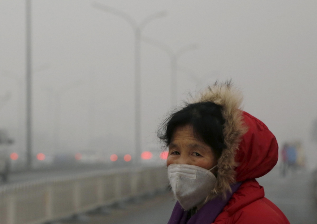 A woman wears a protective mask on one of the worst polluted days in Beijing. The capital city is enveloped in thick smog that has forced schools to close and residents to remain indoors