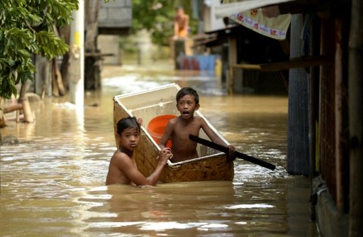 Children use a refrigerator as a boat to cross a flooded alley in Candaba Pampanga north of Manila