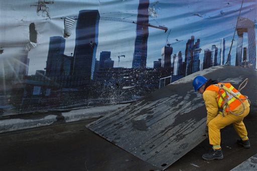 18 2015 a worker moves a metal plate near a billboard showing the Central Business District in Beijing. In a statement issued Monday following an annual planning meeting Chinese leaders promised Monday to promote