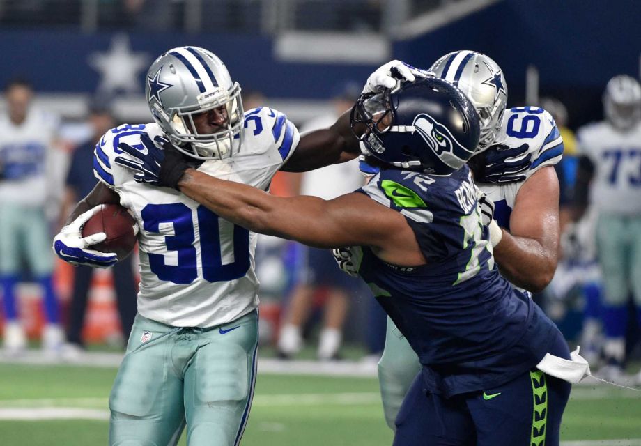 Dallas Cowboys Christine Michael fights off a tackle by Seattle Seahawks defensive end Michael Bennett in the first half of an NFL football game Sunday Nov. 1 2015 in Arlington Texas