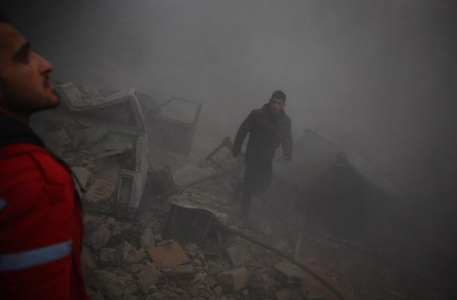 A member of the Syrian Arab Red Crescent and a man look for survivors amid the rubble following airstrikes in the rebel-held town of Douma on the eastern edges of the Syrian capital Damascus