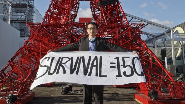 A representative of a NGO displays a banner supporting a target to keep global warming below 1.5 degrees in front of a reproduction of the Eiffel tower at the Paris climate summit