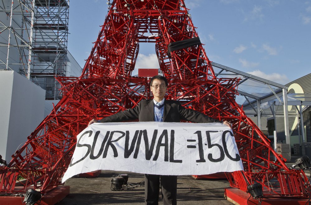 An NGO representative displays a banner in front of a reproduction of the Eiffel Tower in Paris amid a push by smaller countries to make the official target for global warming a threshold of 1.5 degrees Celsius