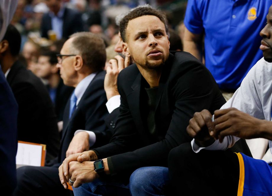 Golden State Warriors Stephen Curry watches from the bench during the first half the team's NBA basketball game against the Dallas Mavericks Wednesday Dec. 30 2015 in Dallas. Curry missed the game due to an injury