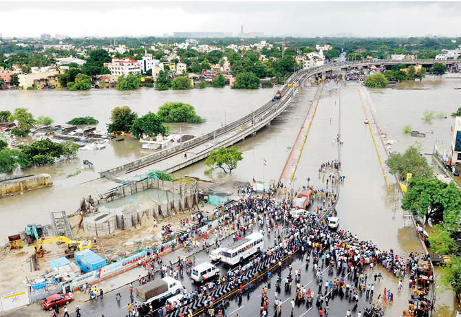 Dead end? People gather as floodwaters lap at the end of a highway in Chennai. pics  pti