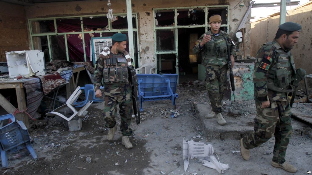 Afghan security forces look at the damage from clashes between Taliban fighters and Afghan forces in Kandahar Airfield Afghanistan Wednesday Dec. 9 2015