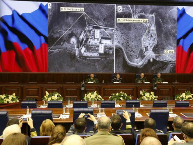 Defence ministry officials sit under screens with satellite images on display during a briefing in Moscow Russia