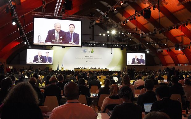 Delegates listen to French Foreign Minister Laurent Fabius speaking during a plenary a session at the COP21 United Nations climate change conference in Le Bourget outside Paris