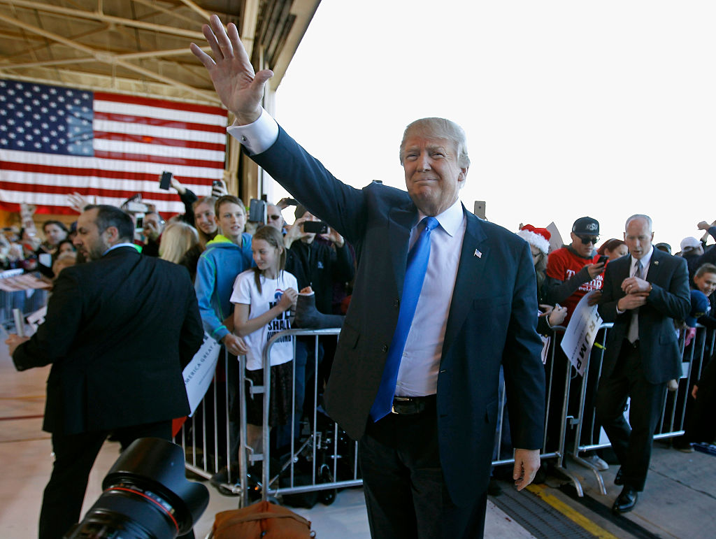 Donald Trump waves to the crowd as he arrives at a campaign event at the International Air Response facility