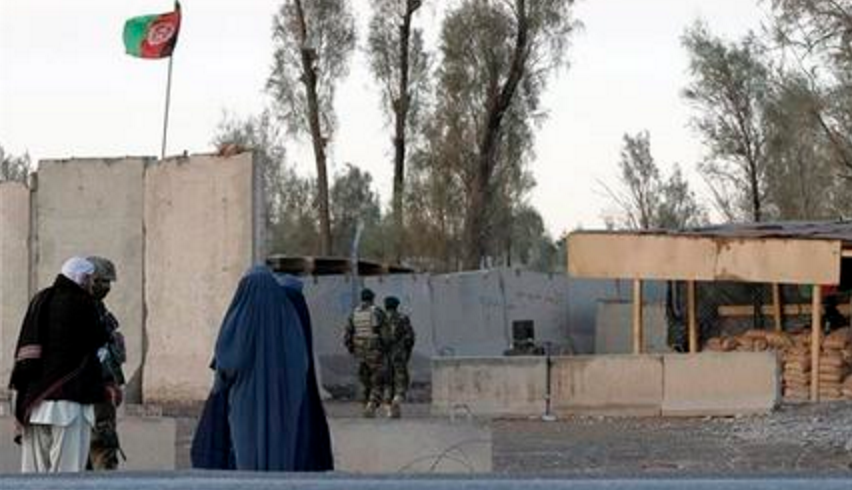 Civilians wait as Afghan security forces guard at the main gate of Kandahar civilian airport during a clash between Taliban fighters and Afghan forces in Kandahar Afghanistan Wednesday Dec. 9 2015. An Afghan official says the Taliban have launched