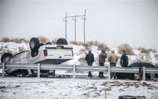 People stand by after a rollover accident along Interstate 25 northbound just south of Albuquerque N.M. Saturday Dec. 26 2015. A flurry of snow began to blanket Albuquerque Santa Fe and other cities Saturday afternoon amid warnings of a record-setti