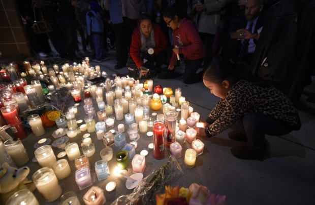 Two-year-old Trinity Cuellar places a candle during the candlelight vigil at San Manuel Stadium to honour the vicitms of the San Bernadino shootings