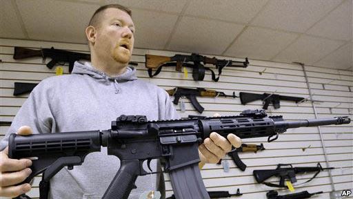 FILE – A gun shop owner in Illinois shows off an AR-15 assault rifle