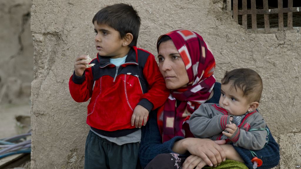 FILE- Members of a Syrian Kurdish refugee family from Kobani sit in the village of Alanyurt on the Turkish side of the Turkey Syria border