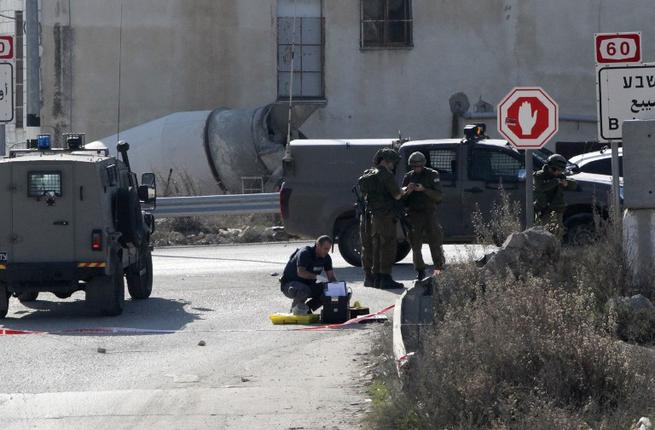 Israeli soldiers and policemen inspect the scene where a Palestinian assailant was shot dead after he tried to stab Israeli security forces with a screwdriver south of the West Bank city of Hebron