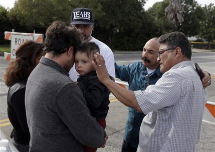 A group of local church members pray for residents who live in the neighborhood where Wednesday's police shootout with suspects took place Thursday Dec. 3 2015 in San Bernardino Calif. Multiple attackers opened fire on a banquet at a social serv