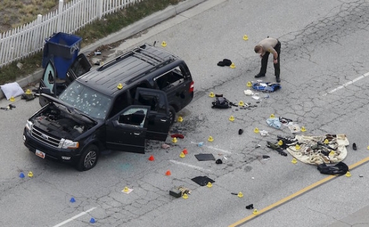 A law enforcement officer looks over evidence near the remains of a SUV involved in the Dec. 2 attack in San Bernardino Calif