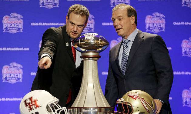 Houston head coach Tom Herman left and Florida State head coach Jimbo Fisher talk with one another while posing with the trophy during a press conference for the Peach Bowl NCAA college football game Wednesday Dec. 30 2015 in Atlanta. Houston plays F