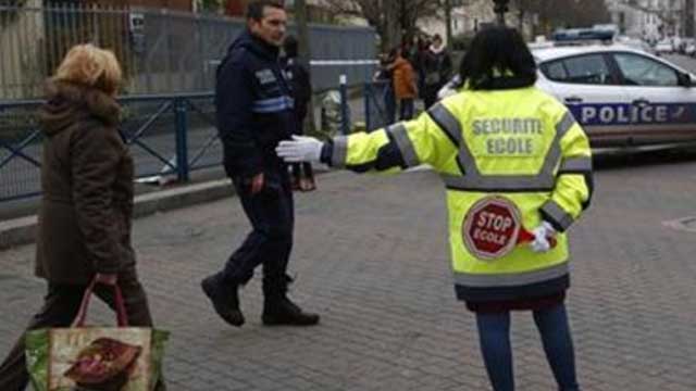 A municipal employee directs the trafic near a pre-school after a masked assailant with a box-cutter and scissors who mentioned the Islamic State group attacked a teacher Monday Dec.14 2015 in Paris suburb Aubervilliers. The assailant remains at large