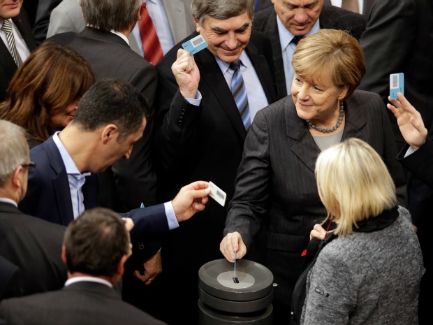 German Chancellor Angela Merkel right casts her vote at the German Federal Parliament in Berlin as the Germany votes to join in anti-ISIL activities in Syria