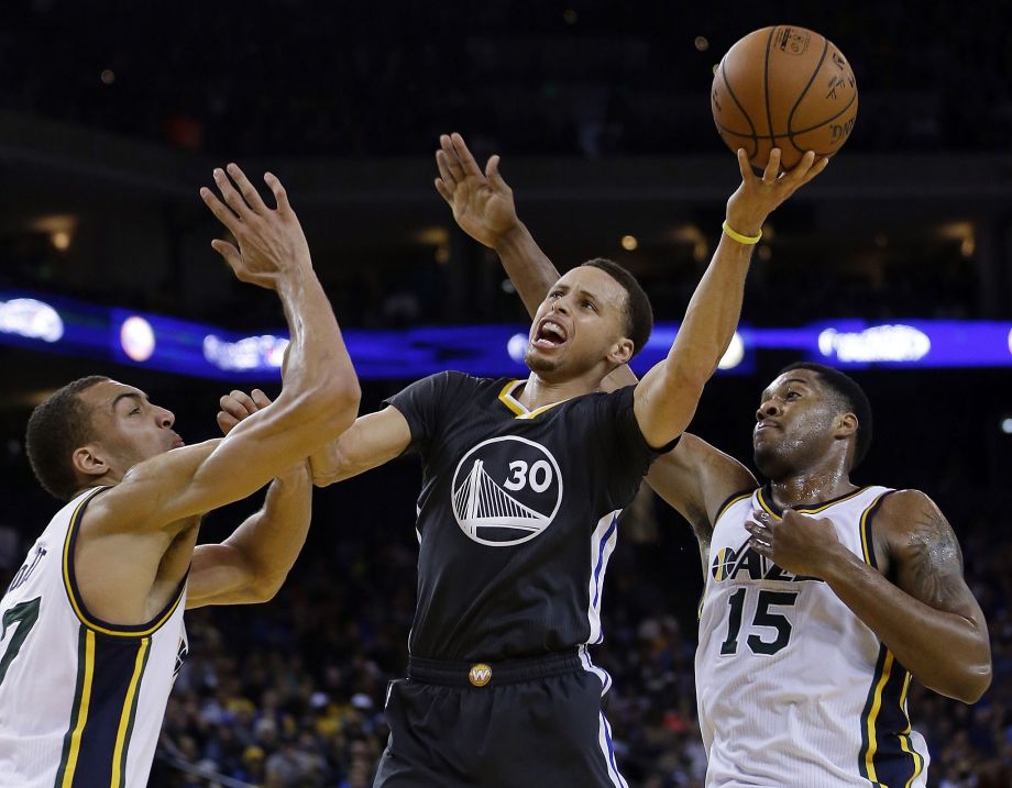 Golden State Warriors Stephen Curry center shoots between Utah Jazz's Rudy Gobert left and Derrick Favors during the second half of an NBA basketball game Saturday