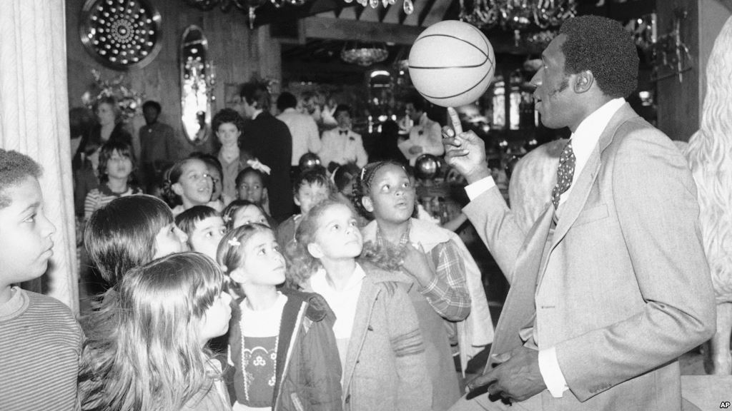 Harlem Globetrotter Meadowlark Lemon balances a basketball on his finger for children attending a children's benefit toy auction at New York's Tavern on the Green