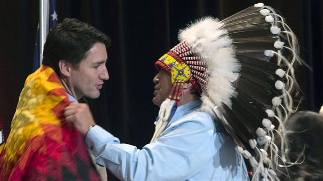 Assembly of First Nations National Chief Perry Bellegarde adjusts a blanket presented to Canadian Prime Minister Justin Trudeau following speeches at the AFN Special Chiefs Assembly in Gatineau