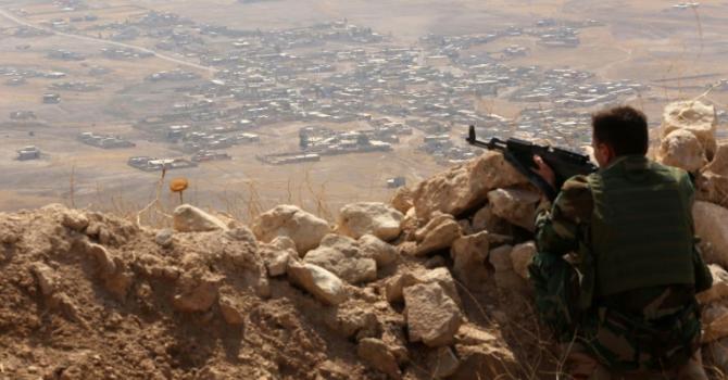 An Iraqi Kurdish Peshmerga fighter monitors his surrounding from the top of Mount Zardak about 25 kilometres east of Mosul