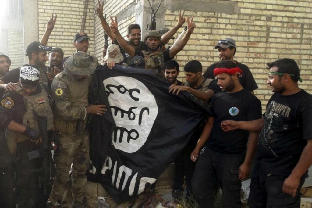 Iraqi security forces stand with an Islamist State flag which they pulled down at the University of Anbar in Anbar province