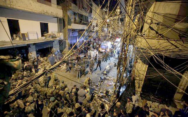 Residents and Lebanese army members inspect a damaged area caused by two explosions in Beirut's southern suburbs Leban