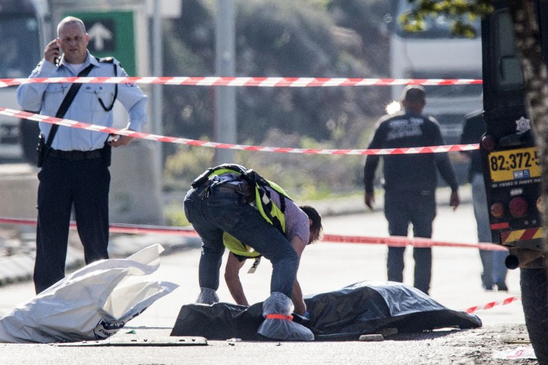 An Israeli forensic policeman stands next to the body of a Palestinian assailant who was shot dead after he stabbed two Israeli security guards at the Barkan Industrial Zone next to the settlement of Ariel