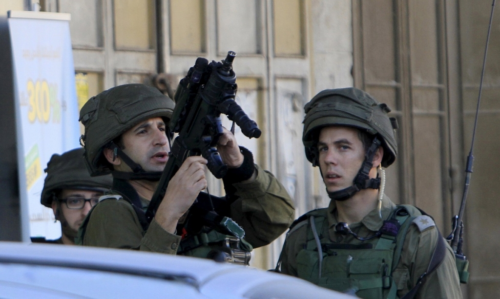 Israeli soldiers stand guard near the scene where two Palestinians who the Israeli military said stabbed and wounded an Israeli soldier were shot dead by Israeli forces in the village of Hewara near the West Bank city of Nablus today. – Reuters pic