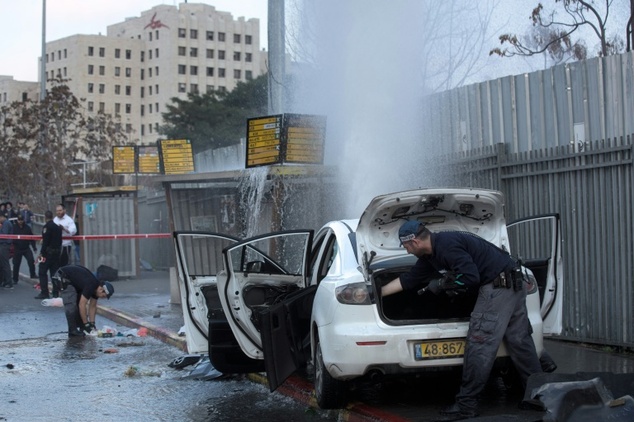 Israeli policemen inspect the car of a Palestinian attacker who was shot dead after driving into Israelis at a bus stop