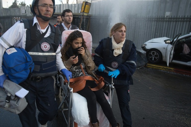 Members of Israeli Magen David Adom rescue service push in wheelchair a young woman who was wounded when a Palestinian attacker drove a car into Israelis