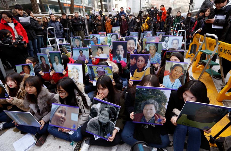 South Koreans hold the portraits of the deceased former South Korean sex slaves who were forced to serve for the Japanese military in World War II during their weekly rally in front of the Japanese Embassy in Seoul South Korea Wednesday Dec. 30 2015