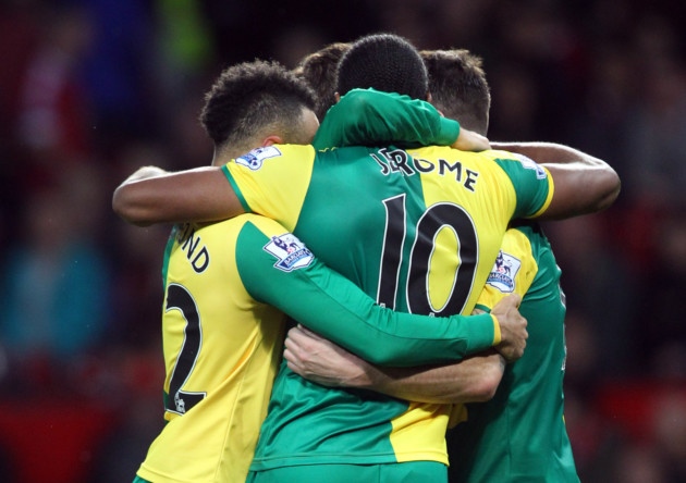 Cameron Jerome is mobbed after setting Norwich City on the way to a 2-1 Premier League win at Manchester United