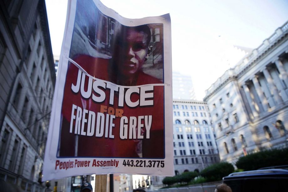 An activist holds a poster outside Baltimore City Circuit Courthouse East during the trial