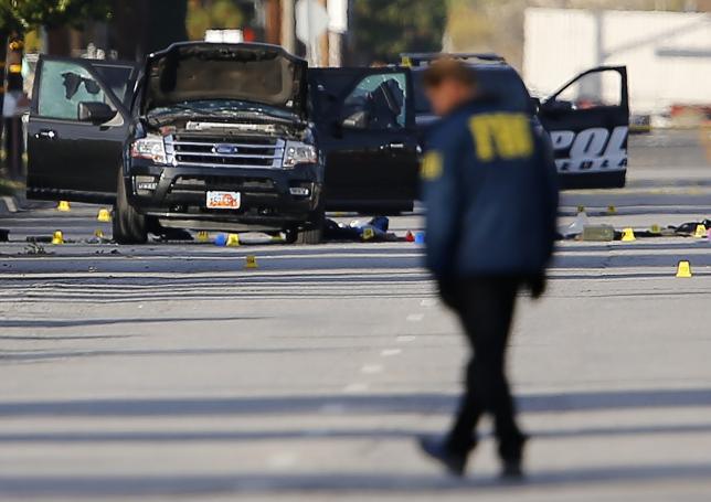 FBI and police continue their investigation around the area of the SUV vehicle where two suspects were shot by police following a mass shooting in San Bernardino California