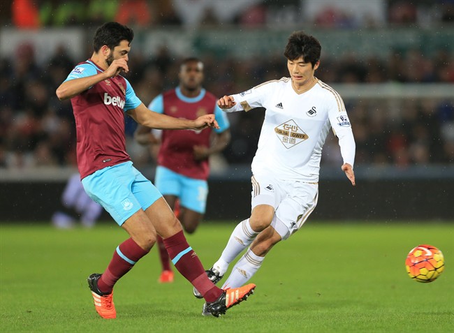 Swansea City's Ki Sung-yueng right and West Ham United's James Tomkins challenge for the ball during the English Premier League match Swansea City versus West Ham United at the Liberty Stadium Swansea Wales Sunday Dec. 20 2015. (Nigel French  PA via