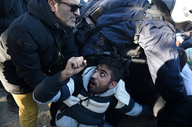 Greek policemen scuffle with stranded migrants who try to block the crossing for refugees at the Greek Macedonian border near the northern Greek village of Idomeni Thursday Dec. 3 2015. Macedonian authorities are allowing only people from the war-wra