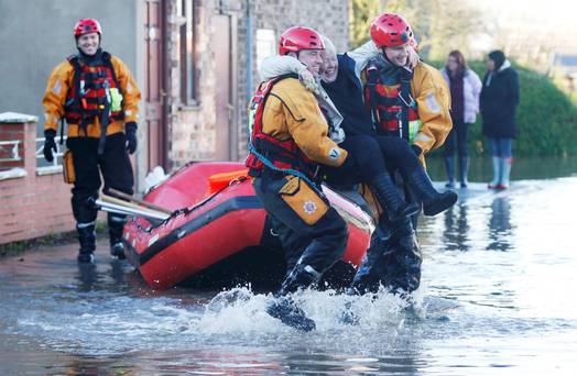 Members of the emergency services rescue a woman from a flooded street in Naburn northern England