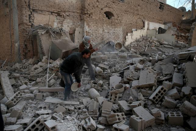 Men search for belongings at a site hit by missiles in the Douma neighborhood of Damascus Syria